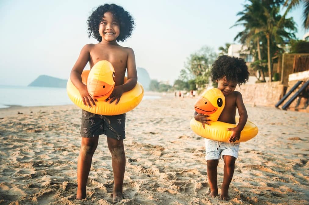 Two children with inflatable rings standing on a beach