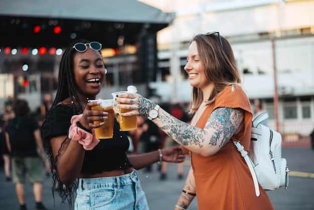 Two girlfriends drinking beer at a festival